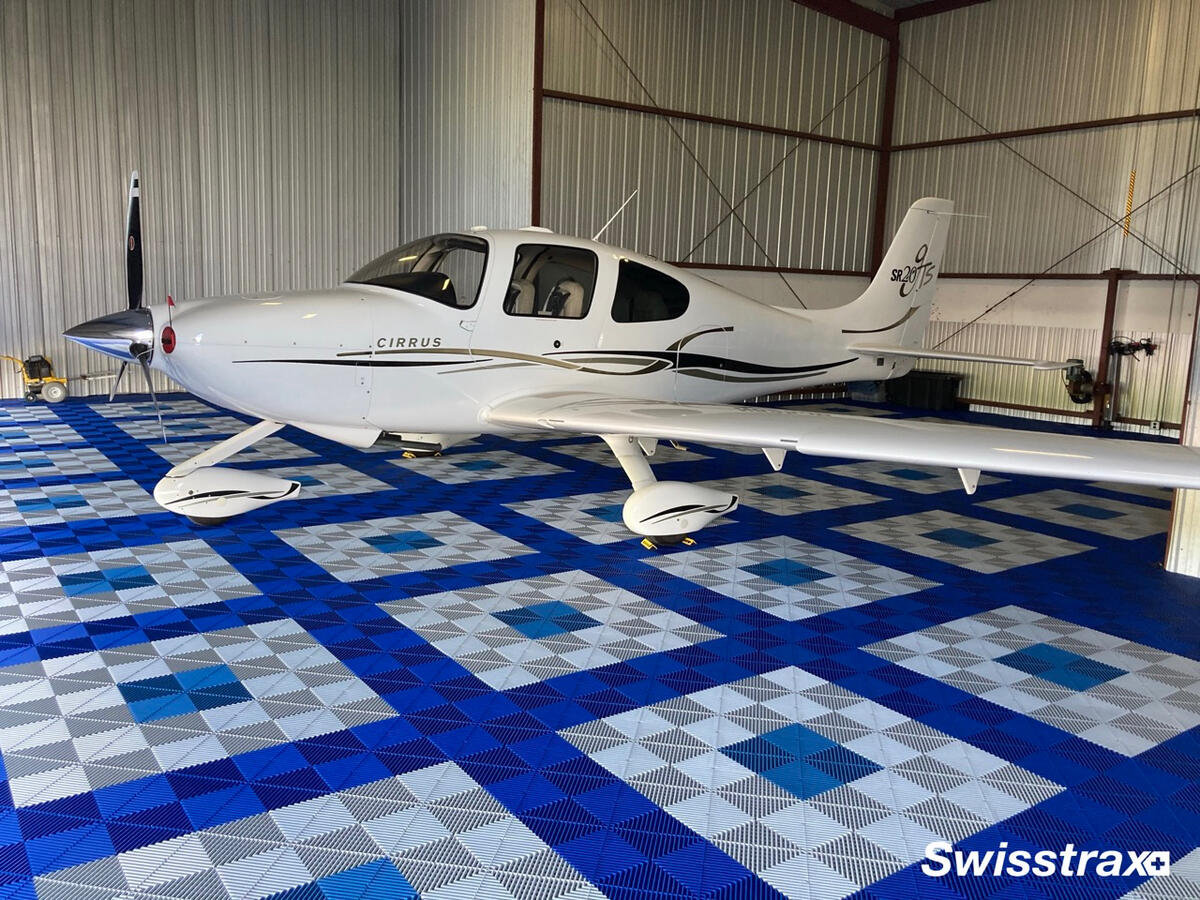 Blue and white Swisstrax hangar floor beneath a small airplane Blue and white Swisstrax hangar floor beneath a small airplane